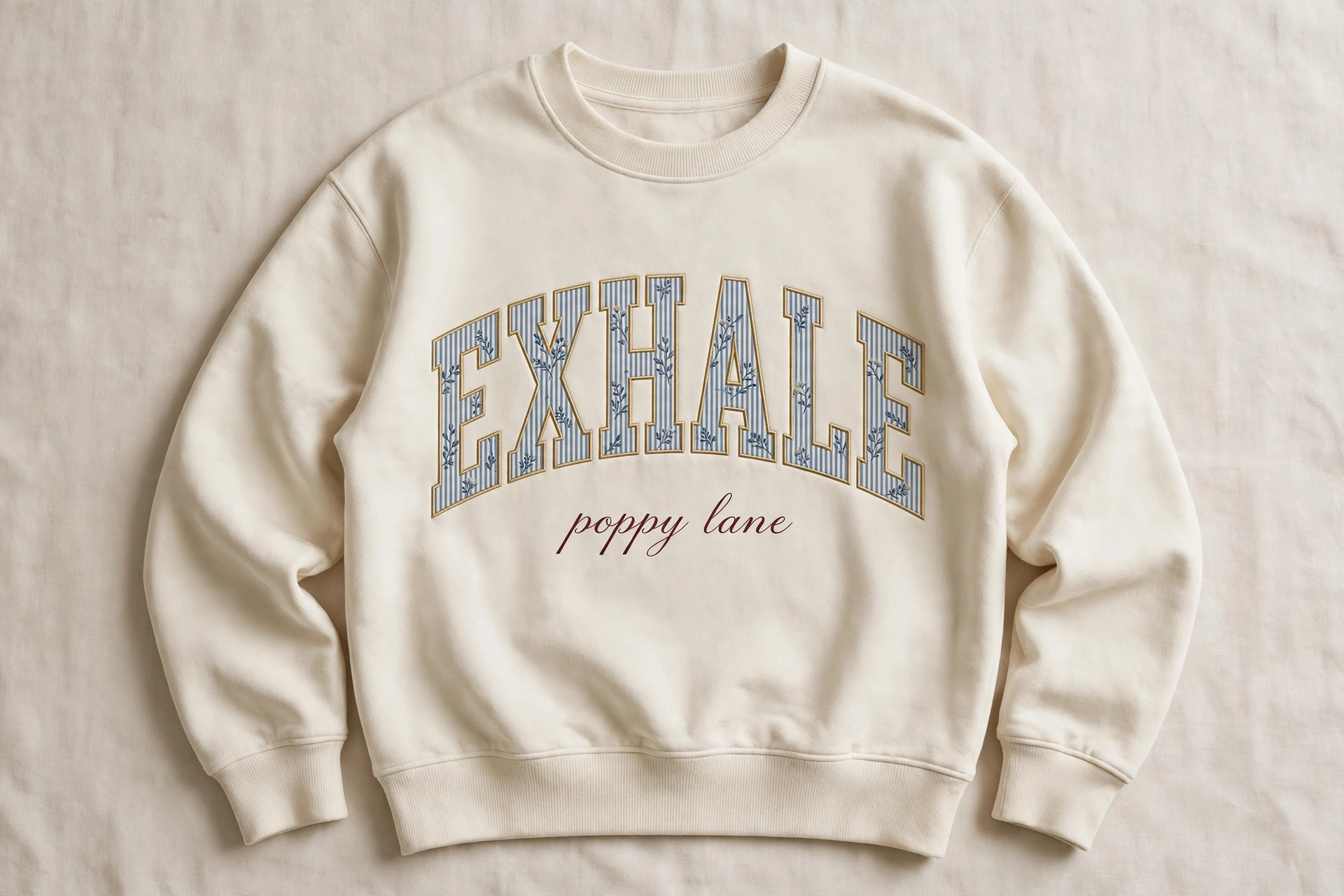 Rendering of a cream crewneck sweatshirt with the word EXHALE in painted collegiate letters across the chest and the words poppy lane in script beneath